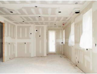 Drywalled room with taped ceiling seams and natural light from a side window